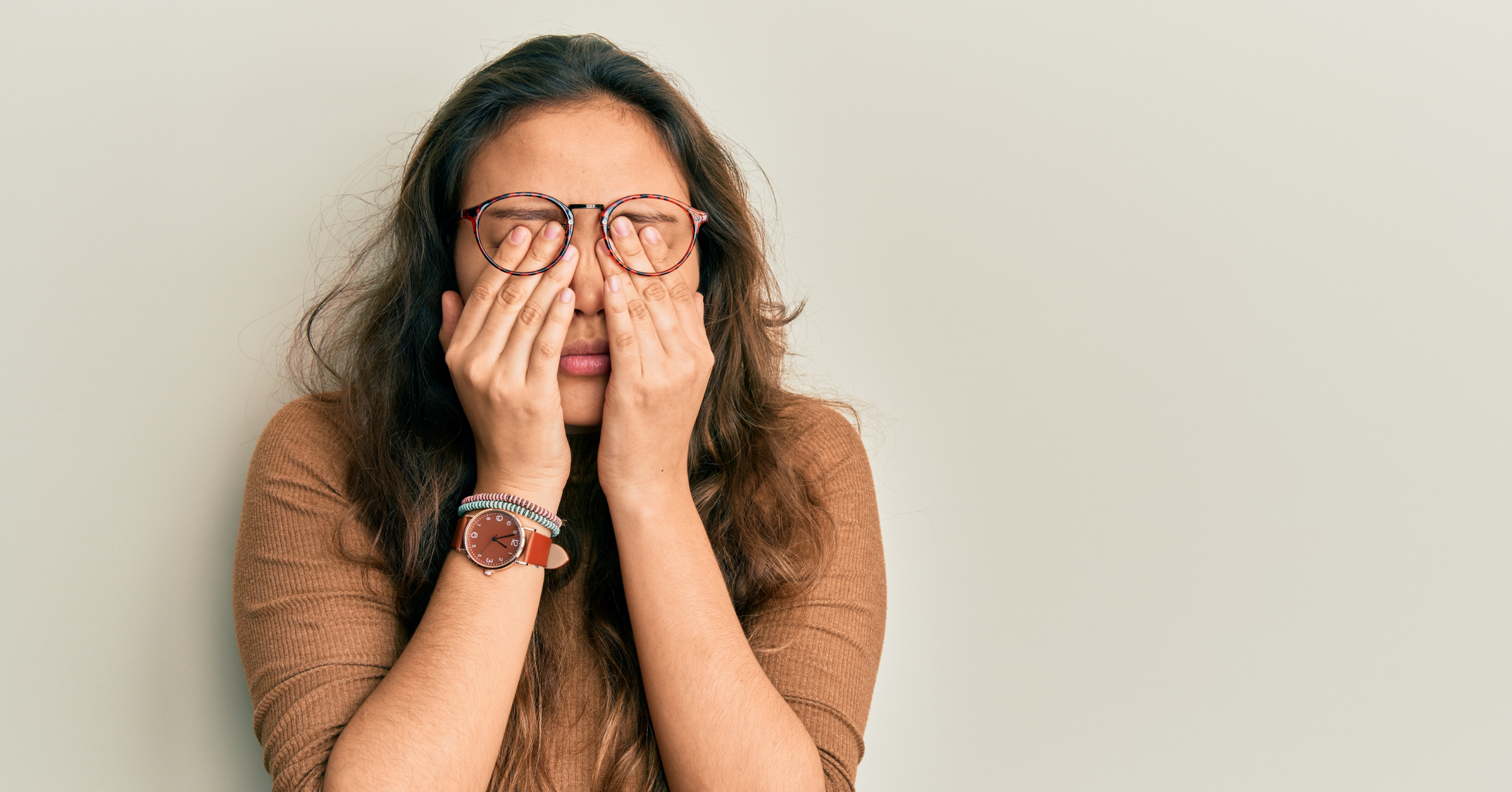 Eine wütende, gestresste Frau reibt sich die Augen. PMDS-Symptome im AMBOSS-Blog.