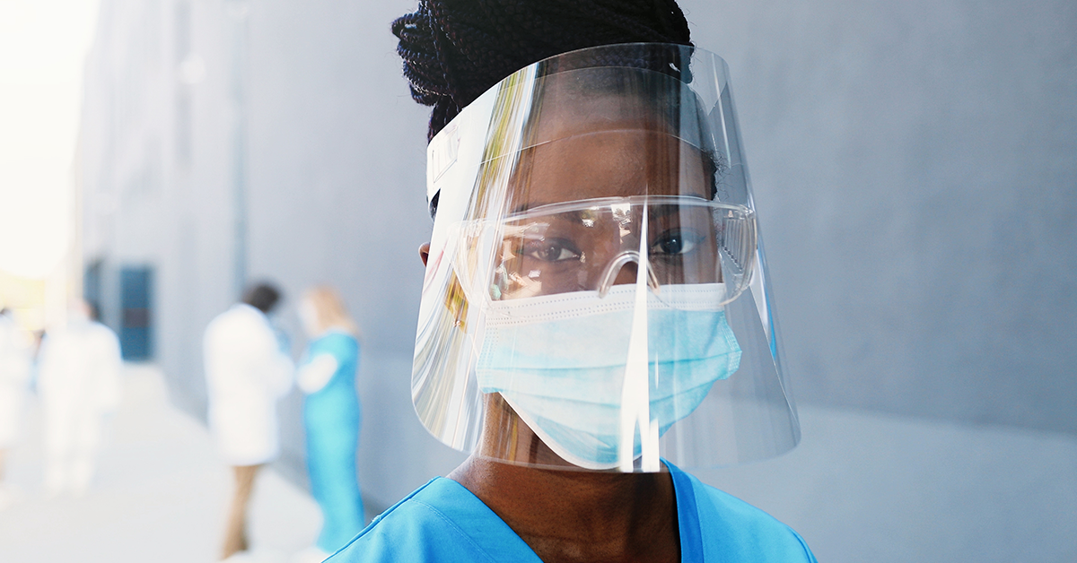 Frau trägt OP-Maske, Schutzbrille und Face Shield.