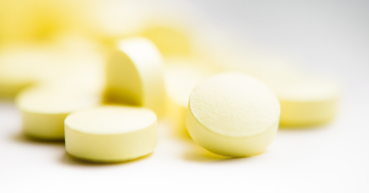 Gelbe Tabletten liegen auf weißer Oberfläche.