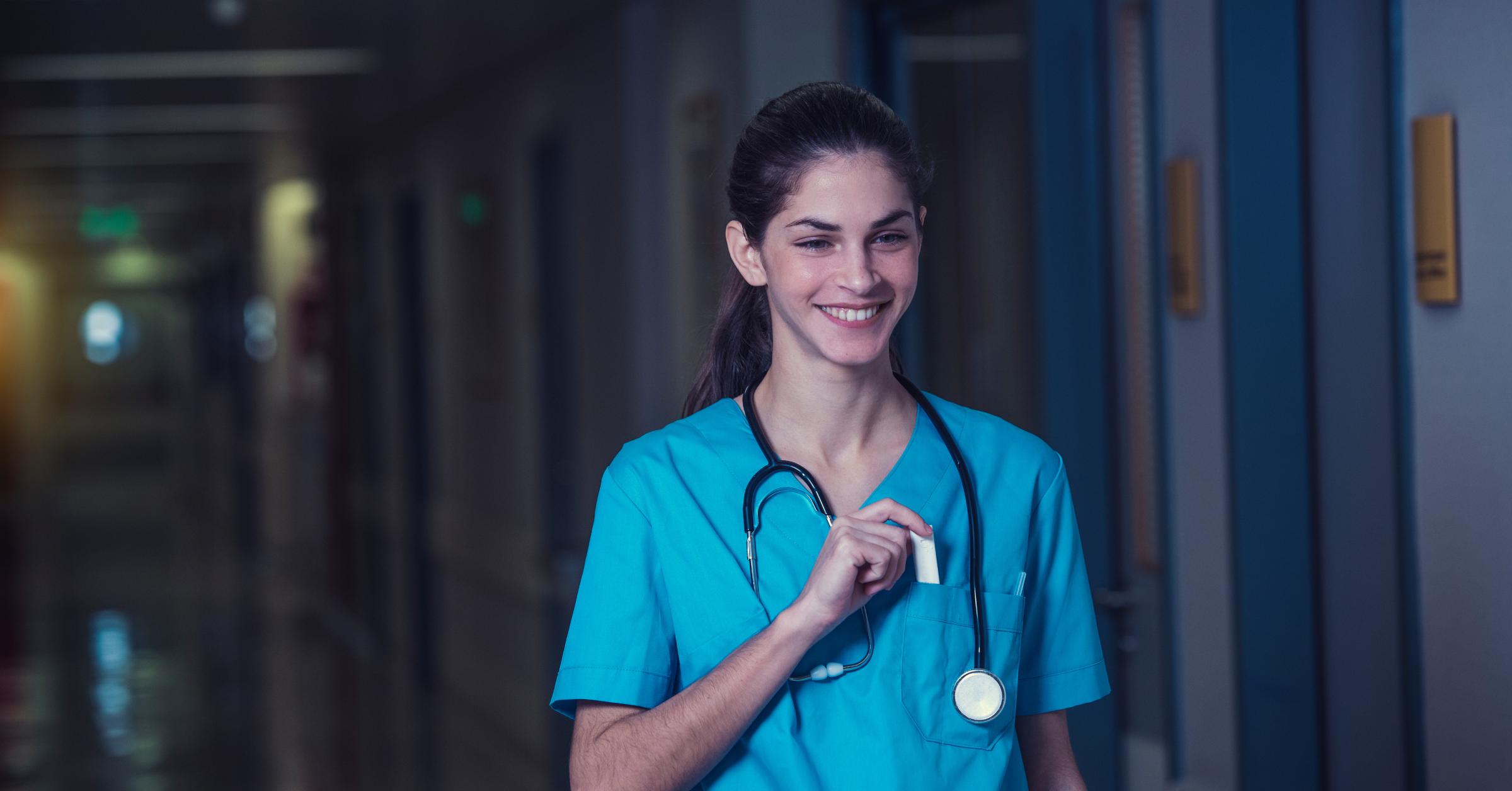 Lächelnde Ärztin auf einem nächtlichen Krankenhausflur. Arbeitszeitmodelle im AMBOSS-Blog.
