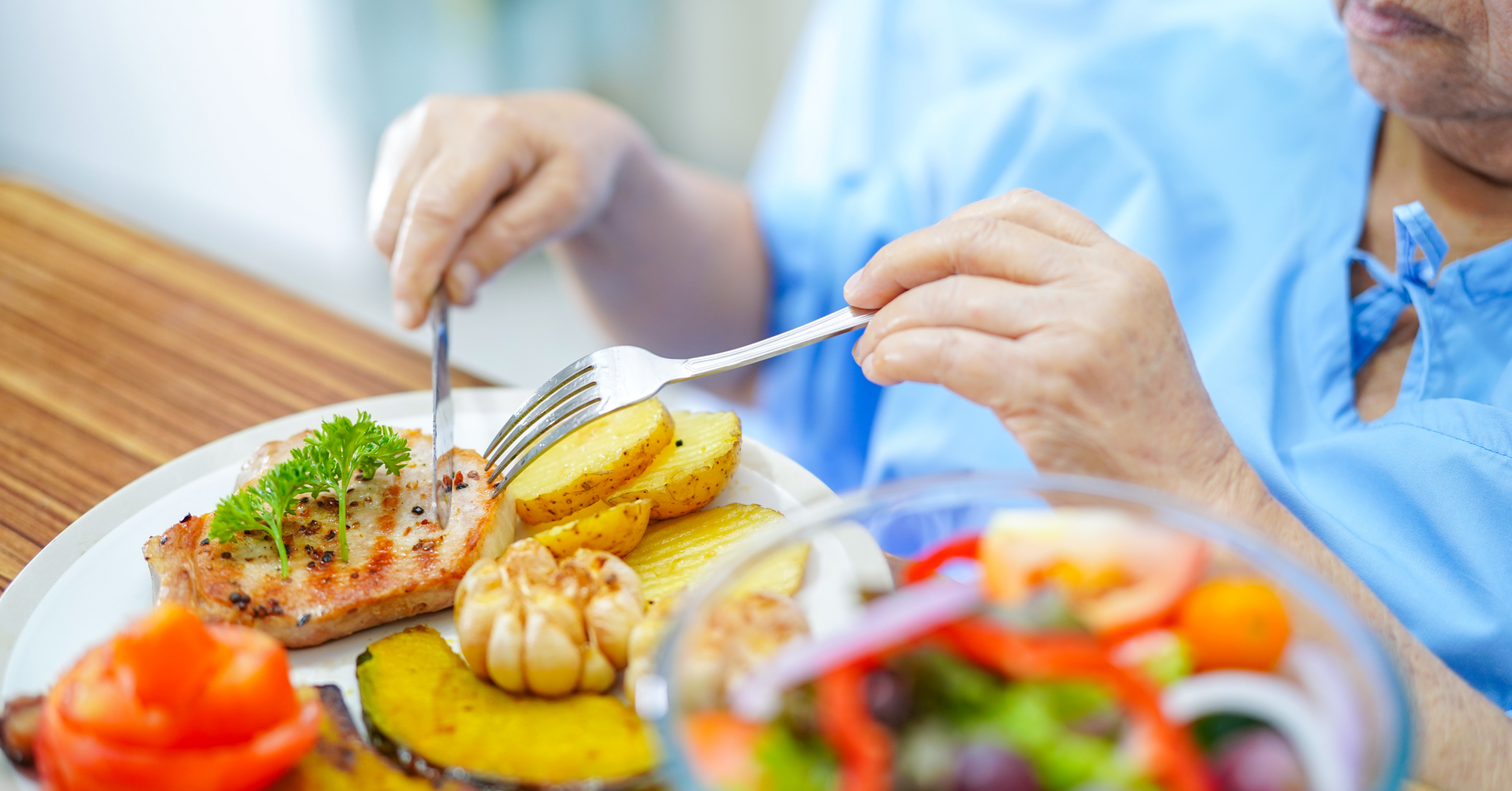 Eine alte Patientin isst ein vegetarisches Mittagessen. Ernährung im Krankenhaus im AMBOSS-Blog.