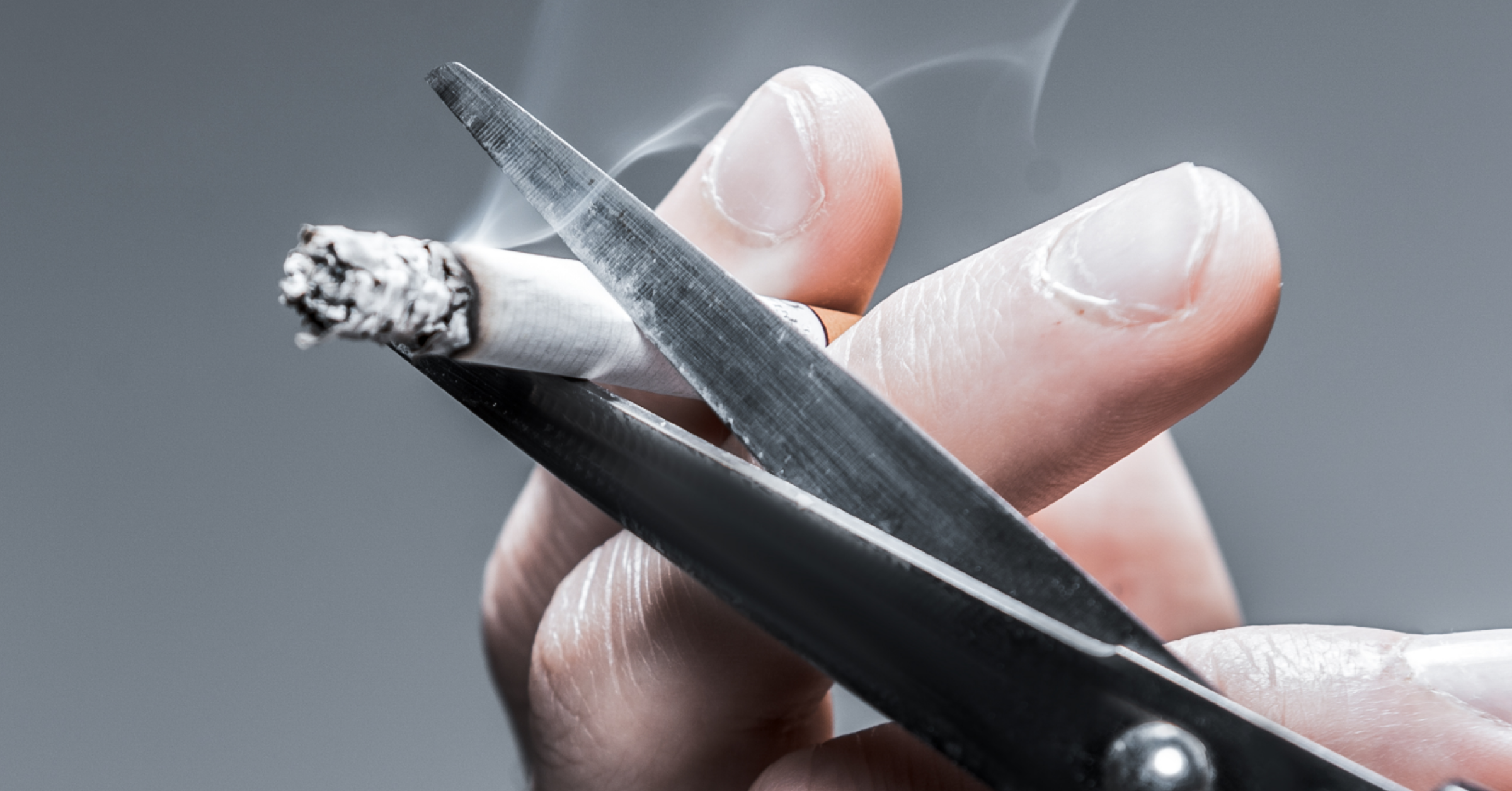 Eine brennende Zigarette wird mit einer Schere zerschnitten. Rauchen aufgeben im AMBOSS-Blog.