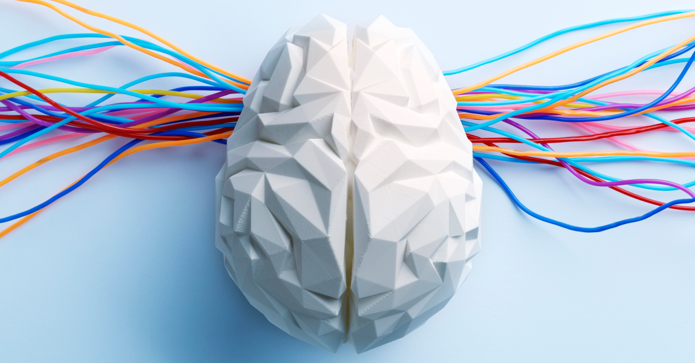 Bunte elektrische Kabel ragen aus einem Gehirnmodell. Elektrokonvulsionstherapie (EKT) im AMBOSS Blog.